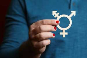 Person zeigt Symbol der Dreigeschlechtlichkei zwischen Daumen und Zeigefinger haltend.