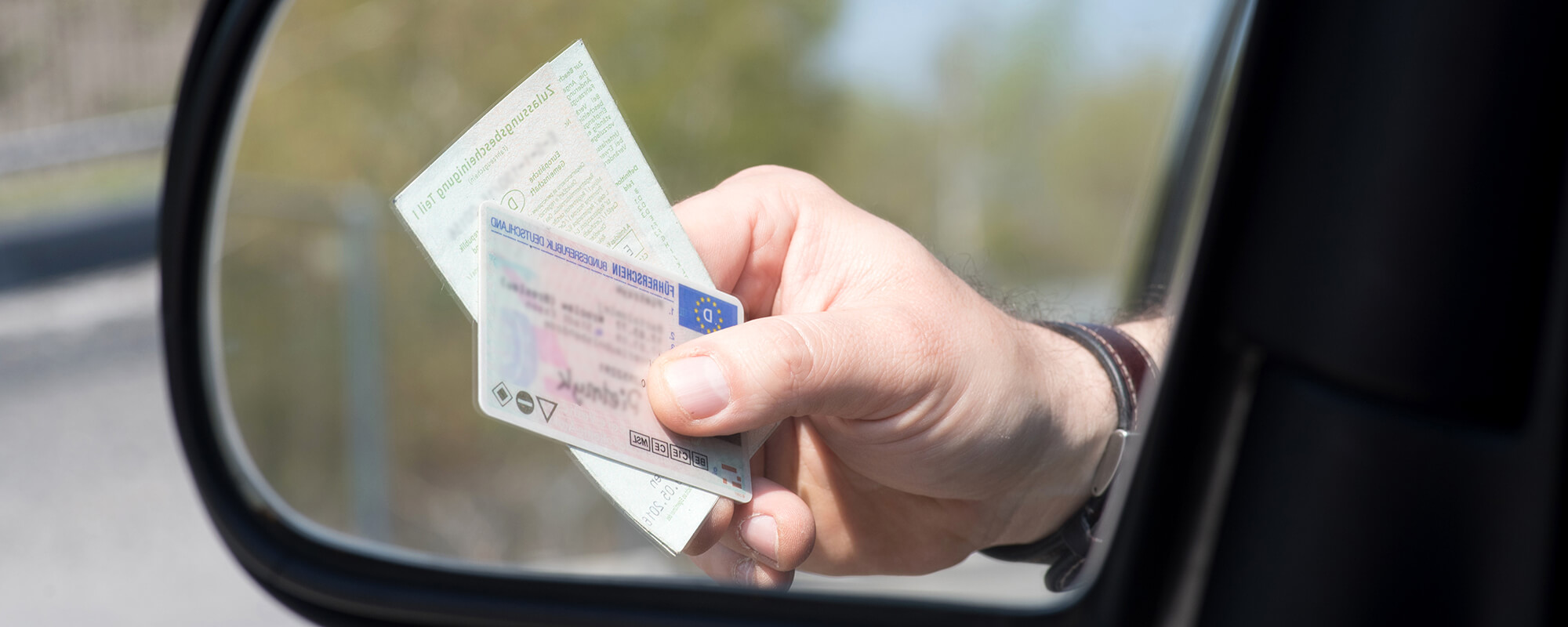 Bussgeldbescheid eine Hand hält den Führerschein und die Papiere