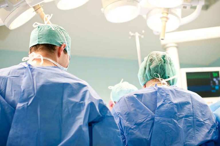 Zwei Ärzte in blauer OP-Kleidung stehen an einem Operationstisch