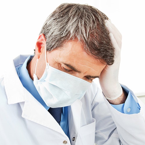 Artzhaftung Arzt nach Behandungsfehler greift sich an den Kopf