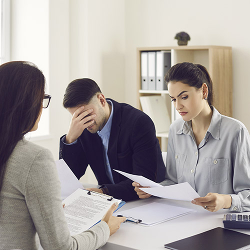 Die Chefin sitzt am Bürotisch und überbringt schlechte Nachrichten an die Mitarbeiter