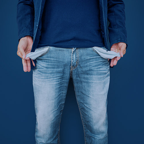 Arbeitsgeber zahlt Lohn nicht Mann zeigt seine leeren Taschen auf Zementwand Hintergrund